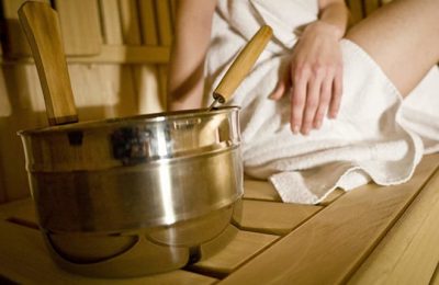 Sauna Frau in weißem Handtuch neben Saunaequipment