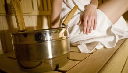 Sauna Frau in weißem Handtuch neben Saunaequipment