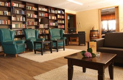 Lounge Innenbereich mit Sessel vor Bücherregal