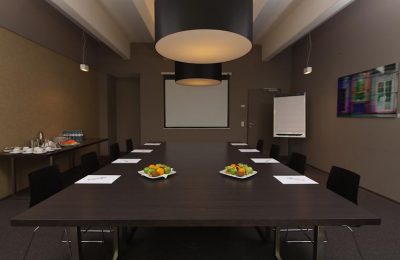 Tagungsraum 2 Schwarzer Tisch mit Stühlen und Leinwand für Tagungen