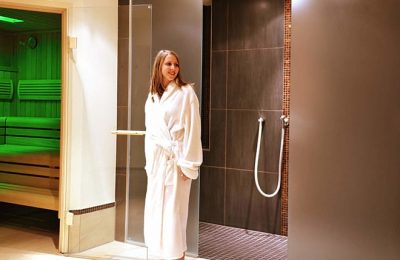 Dampfbad Frau in weißem Bademantel vor Dampfbad