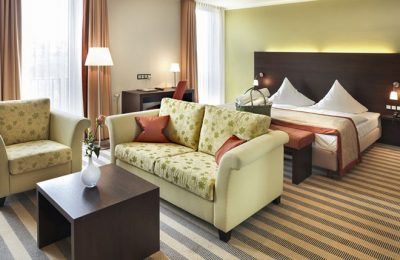 Doppelzimmer im Lichtflügel Bett und Wohnraum mit Sofas im Doppelzimmer im Lichtflügel