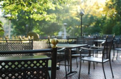 Schlemmergarten 2 Schwarze Tische und Sitzgelegenheiten bei Sonnenschein im Garten