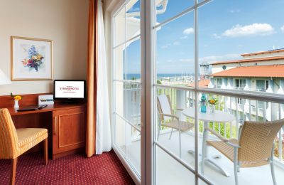 Doppelzimmer mit Meerblick Tisch und Stuhl vor Balkon mit Meerblick im Doppelzimmer