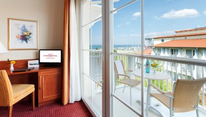 Doppelzimmer mit Meerblick Tisch und Stuhl vor Balkon mit Meerblick im Doppelzimmer
